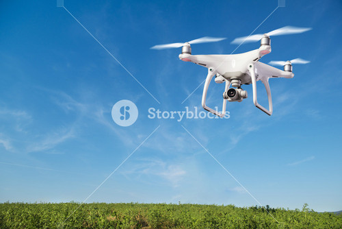 Close Up Of Hovering Drone Against Clear Blue Sky Taking Pictures Of Green Hills