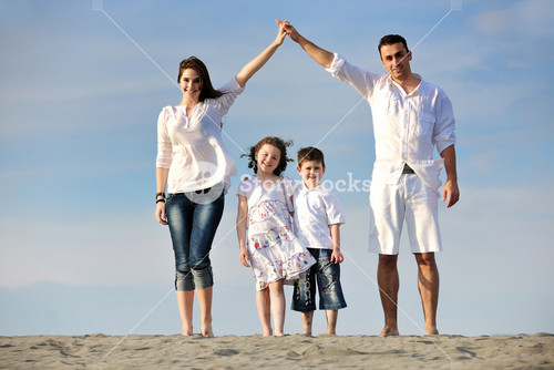 Family On Beach Showing Home Sign