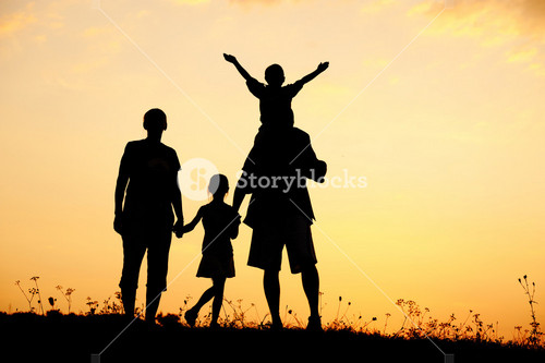 Happy Family On Meadow At Summer Sunset