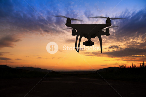 Silhouette Of Hovering Drone Taking Pictures Of Green Meadows And Hills At Sunset