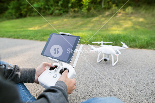 Young Man With Remote Control And Flying Camera Drone. Green Sunny Nature.